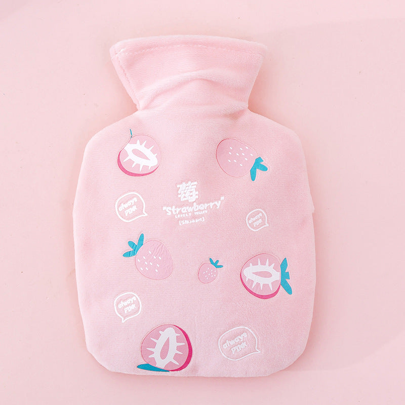 Bouillotte peluche rose à motif fraise, posée à plat sur un fond rose uni, vue de face